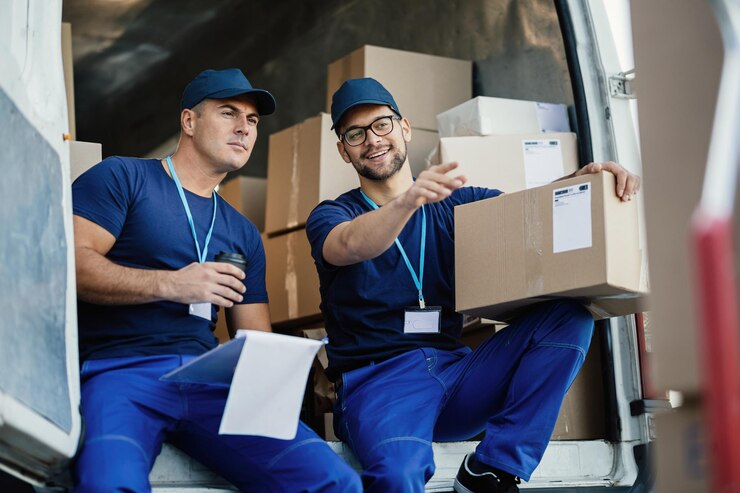 young-courier-pointing-something-while-witting-with-his-coworker-back-delivery-van_637285-2286